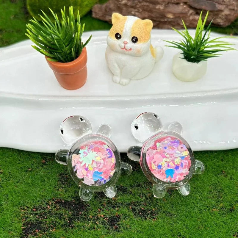 Three small glow-in-the-dark sea turtle figurines are displayed on a white plate with potted greenery.