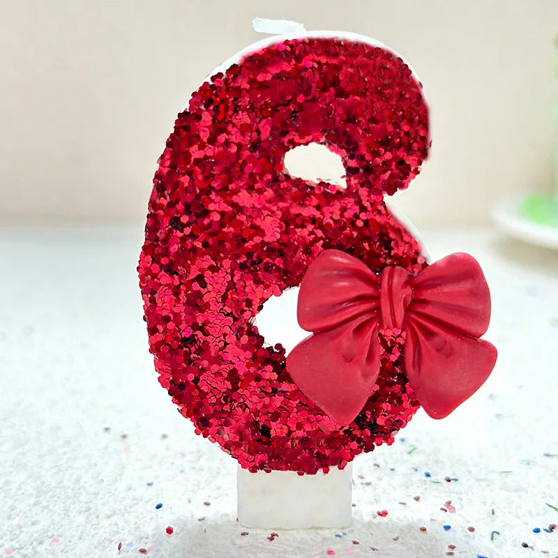 A number eight made of red glittery material with a pink bow, used for birthday and celebration cakes.
