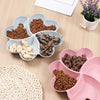 A pink heart-shaped four-compartment snack tray filled with various dry pet treats.