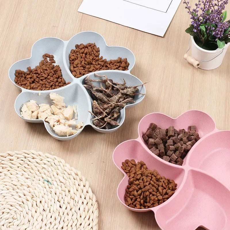 A pink heart-shaped four-compartment snack tray filled with various dry pet treats.