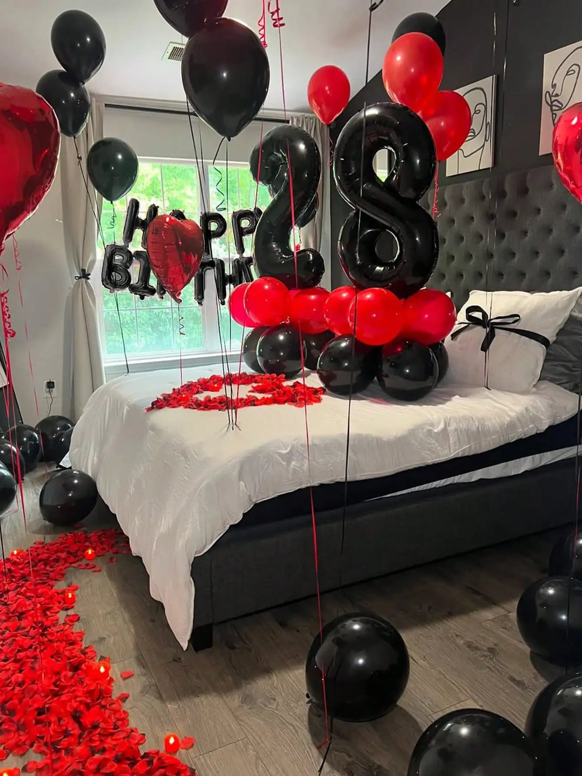 A red and black balloon garland decoration set featuring foil number balloons strung across a bedroom setting.