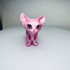 A pink articulated 3D printed figurine of a Siamese cat with large blue eyes.