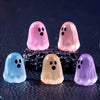 A collection of luminous ghost mini figurines in pink, purple, blue, and yellow resting on a dark surface.