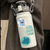 A white water bottle with a gray cap and inspirational quotes printed on the body, hanging from a gray strap.