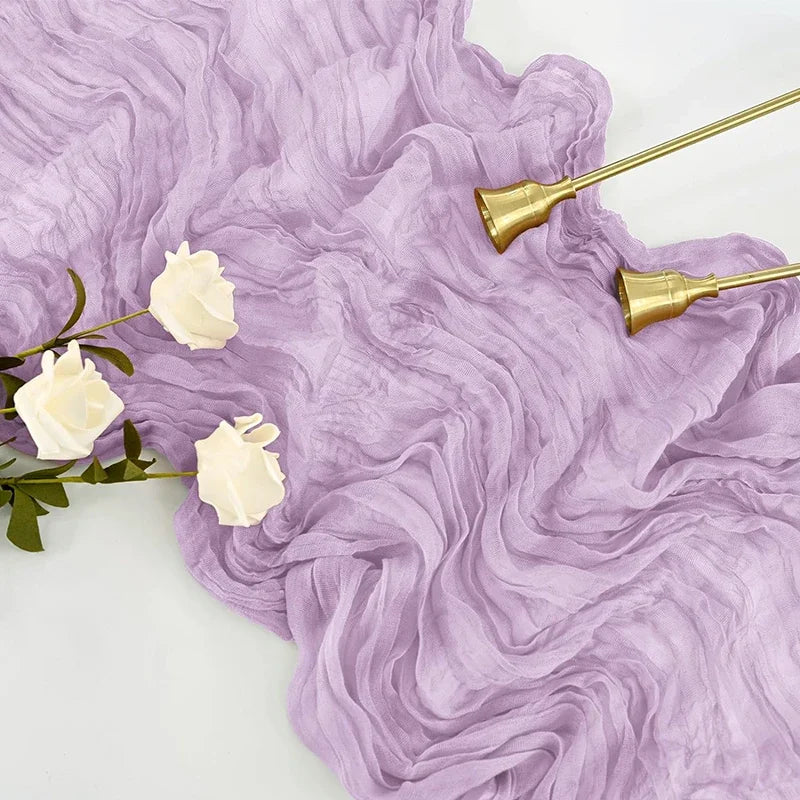 A purple gauze table runner with white flowers and gold-toned accents.