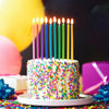 A white cake decorated with colorful sprinkles and topped with lit birthday candles.