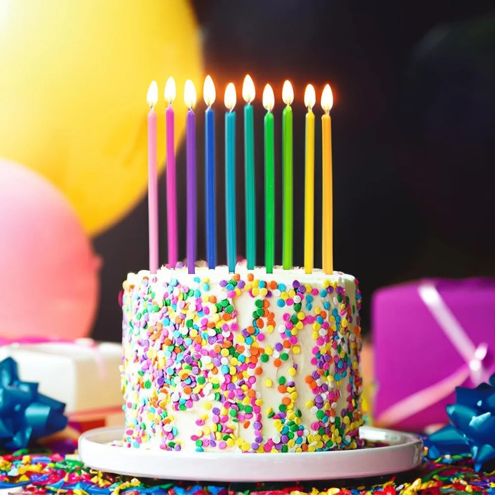A white cake decorated with colorful sprinkles and topped with lit birthday candles.