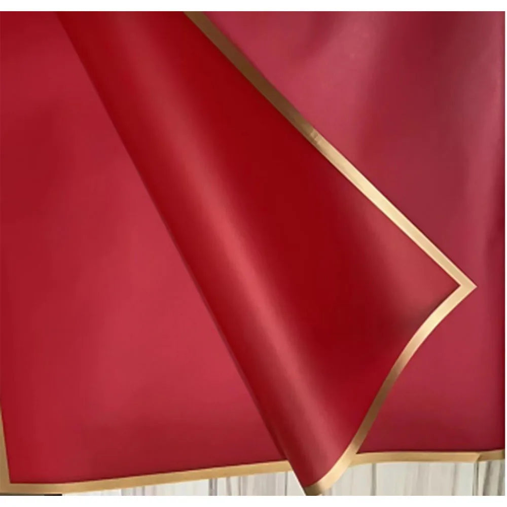 A sheet of deep red satin fabric with a gold edge, shown at an angle.