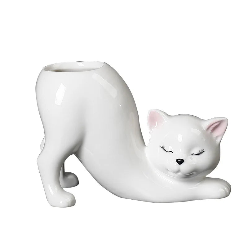 A white ceramic cartoon cat planter shaped like a sleeping cat with a long tail.