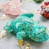 A vibrant turquoise crystal frog resin craft decoration resting on a gray surface.