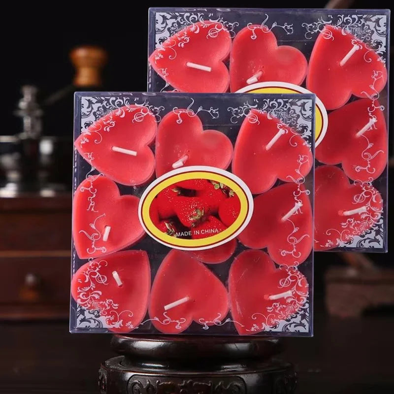 Un ensemble de bougies parfumées en forme de cœur rouges, présentées dans une boîte transparente sur un support en bois.