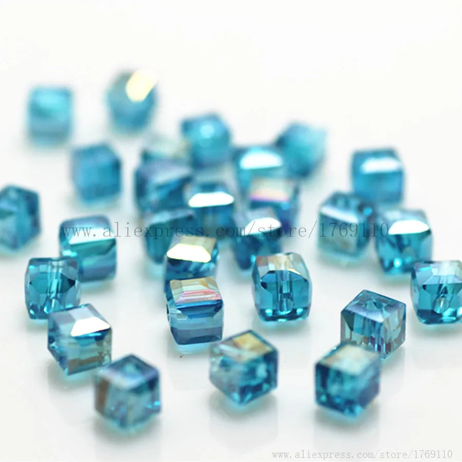 A pile of small, square-cut blue glass crystal beads for jewelry making.