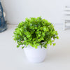 Un vibrant plant de bonsaï artificiel vert dans un pot blanc sur une surface claire.