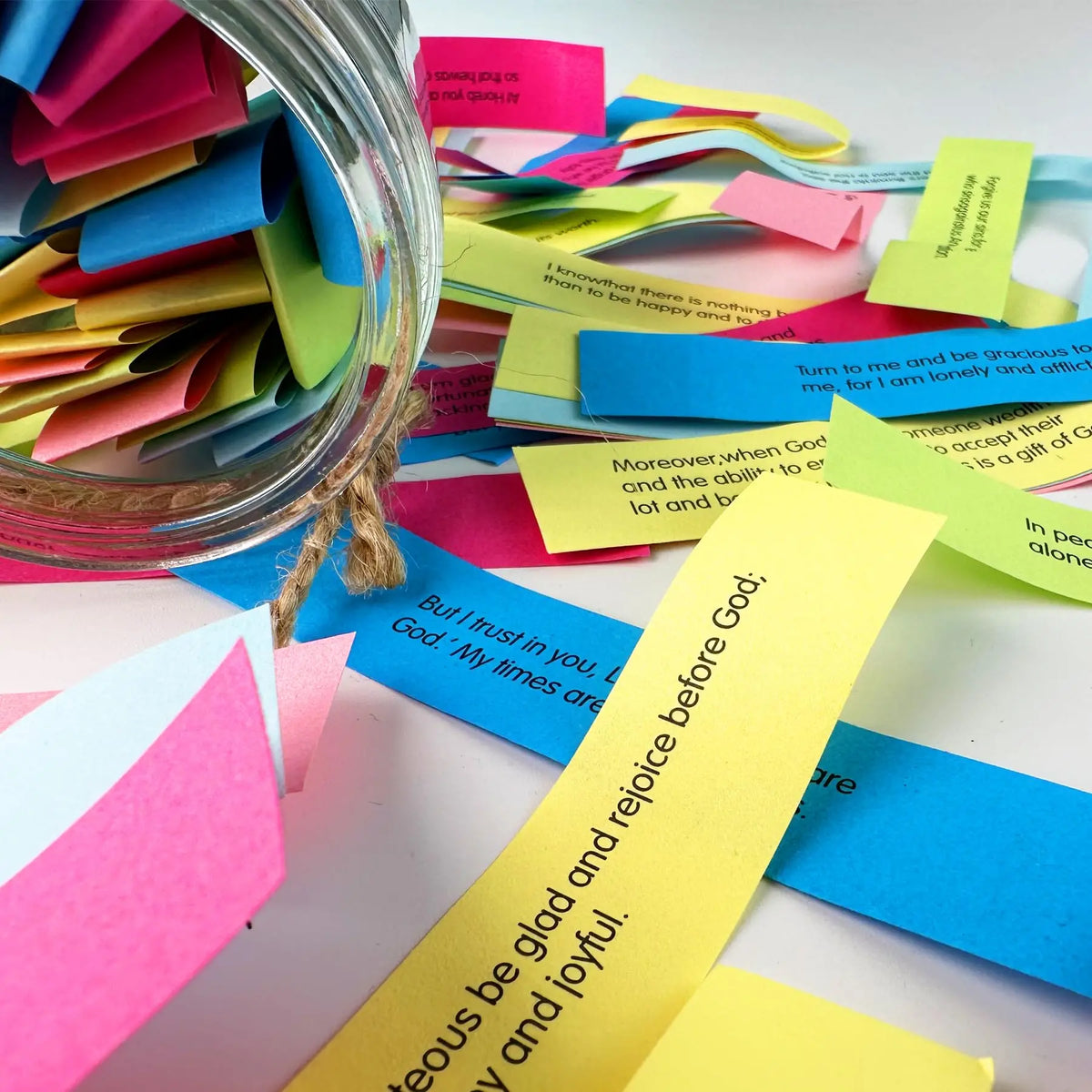 A collection of colorful sticky notes with Bible verses is displayed next to a glass jar.