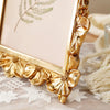 A golden 3D resin photo frame with an elegant floral design and greenery displayed on a light surface.
