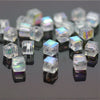 A collection of square cut glass crystals and beads reflecting on a dark surface.