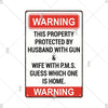 A vintage metal warning sign with red and white text that reads WARNING THIS PROPERTY PROTECTED BY HUSBAND WITH GUN & WIFE WI
