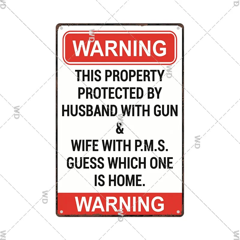 A vintage metal warning sign with red and white text that reads WARNING THIS PROPERTY PROTECTED BY HUSBAND WITH GUN & WIFE WI
