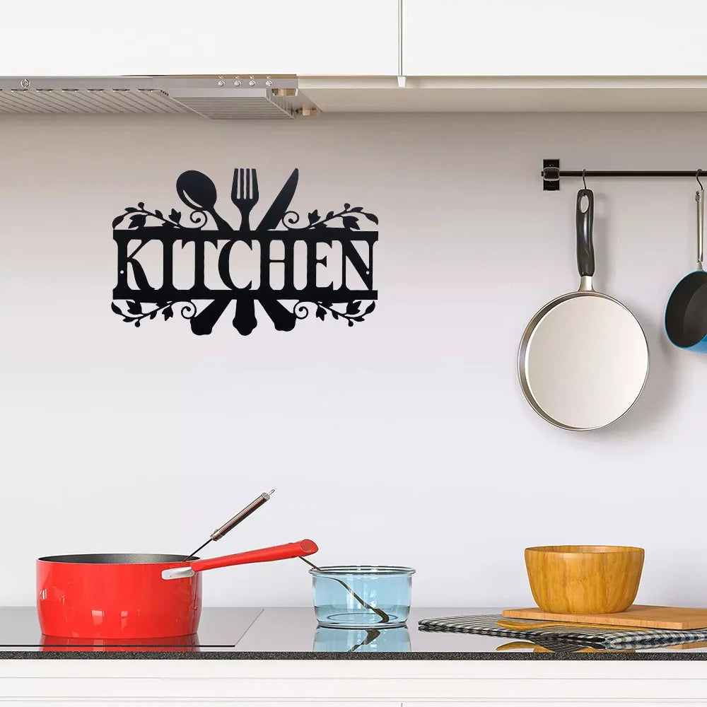 Rustic black metal word sign spelling out KITCHEN mounted on a white wall above a kitchen counter.