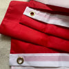 A red and white striped flag banner folded and displayed on a light surface.