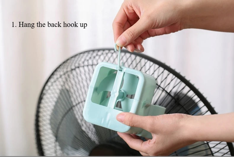 Hands are hanging the back hook onto a portable ice-cooling floor fan.
