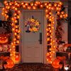 An orange decorative LED string lights garland frames a white door for Halloween decoration.