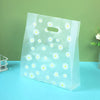 Clear plastic gift bags with daisy print designs displayed on a light blue surface.