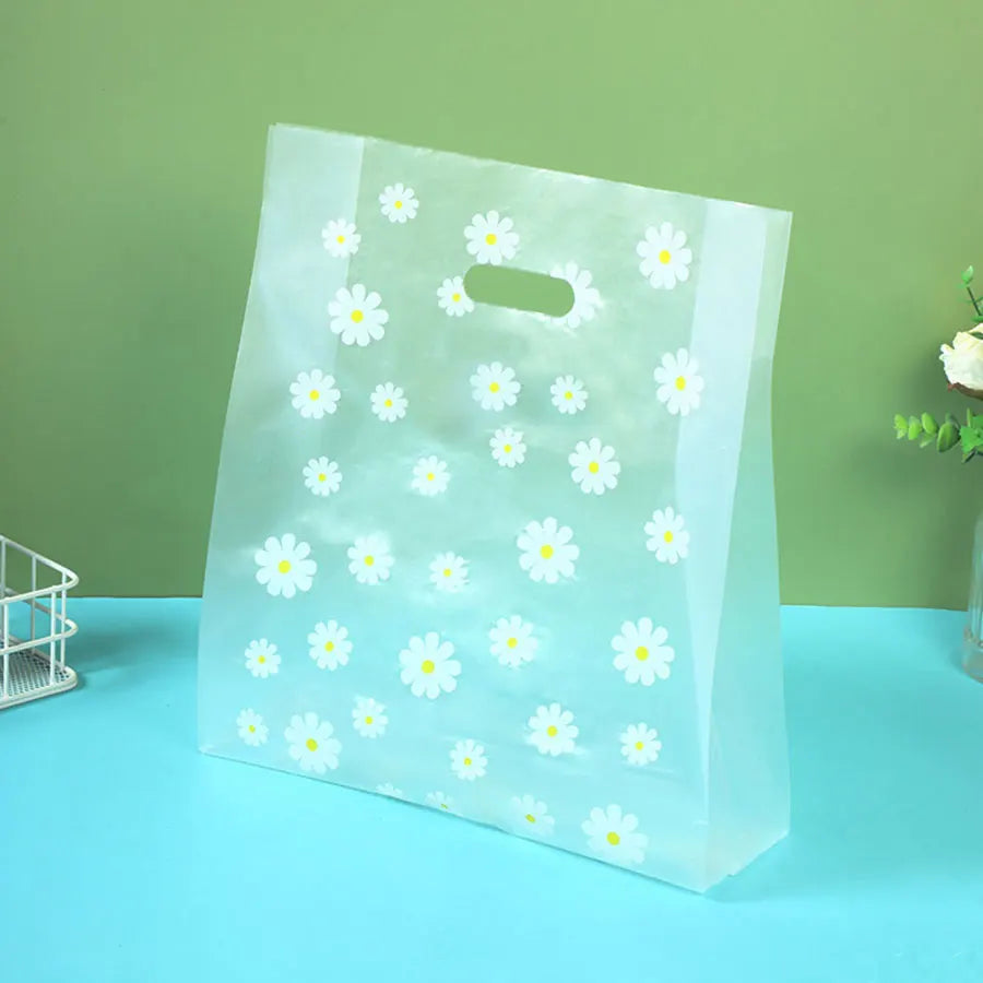 Clear plastic gift bags with daisy print designs displayed on a light blue surface.