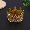 A golden crown tiara with pink and clear stones used as a cake topper or hair accessory.