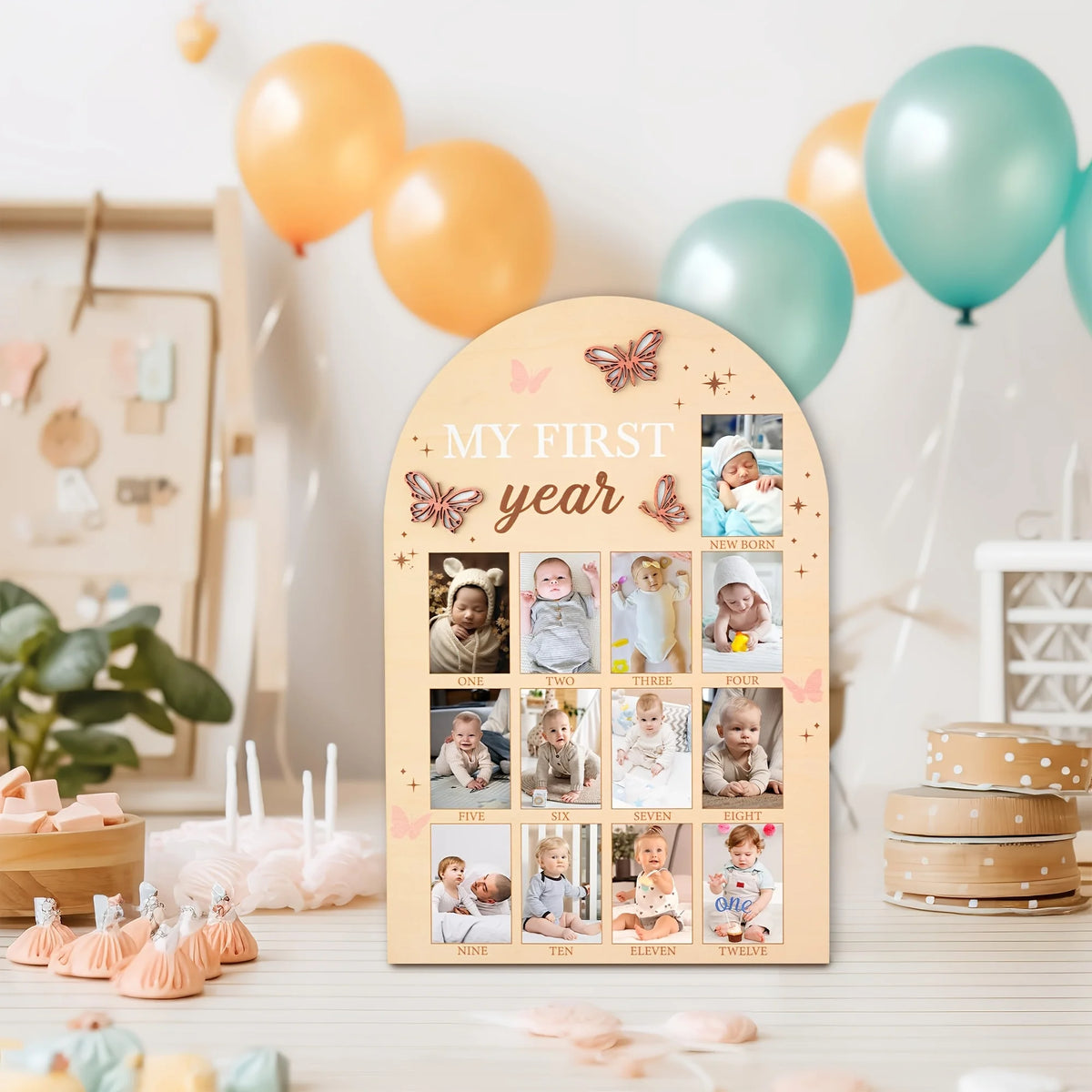 A wooden milestone board featuring photos of a baby from newborn to twelve months, decorated with pink and gold butterflies.