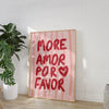 Pink striped canvas wall art featuring the handwritten text MORE AMOR POR FAVOR on a light wood frame