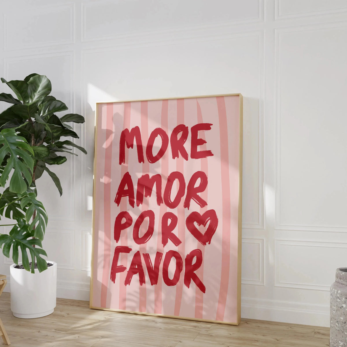 Pink striped canvas wall art featuring the handwritten text MORE AMOR POR FAVOR on a light wood frame