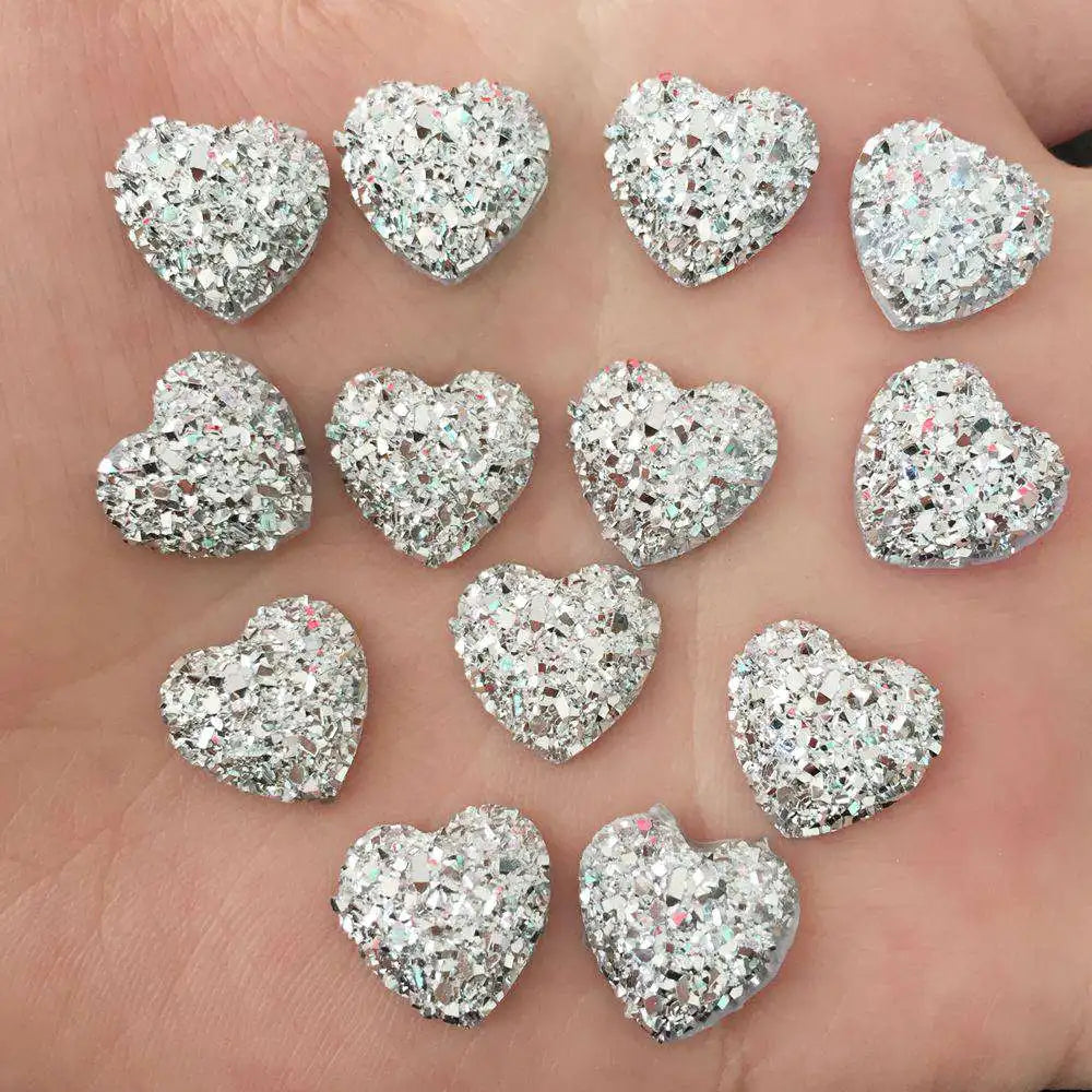 Eine Hand hält mehrere herzförmige Strass-Verzierungen auf der Haut.