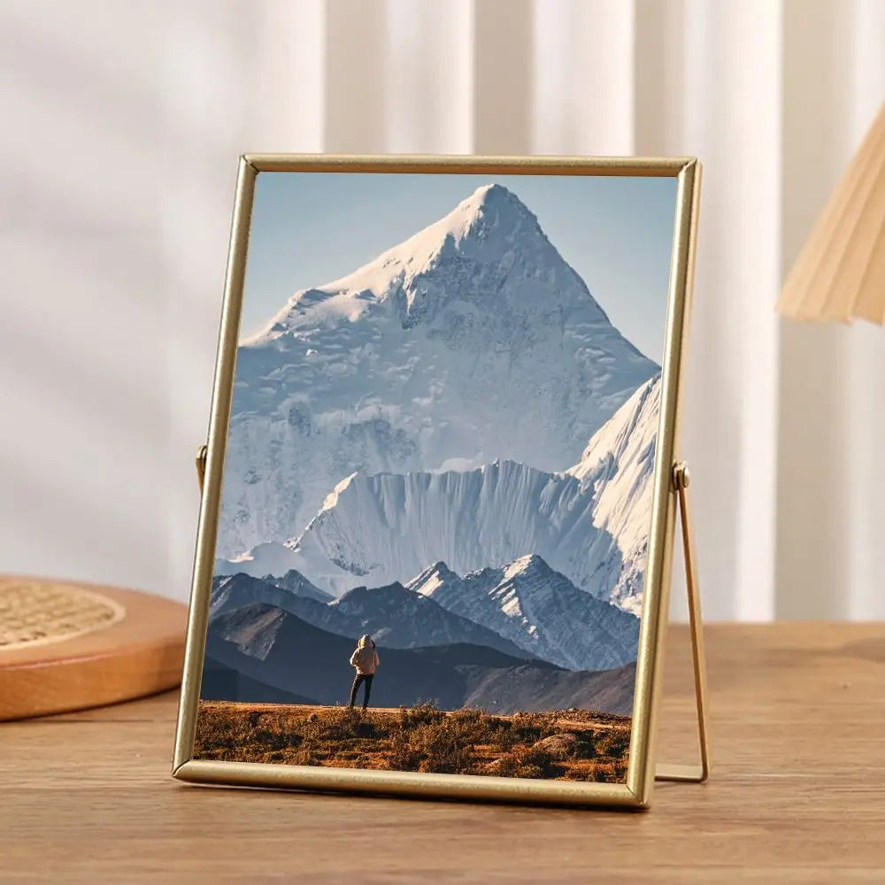 A photo frame displaying a majestic snowy mountain landscape with a person standing in the foreground.