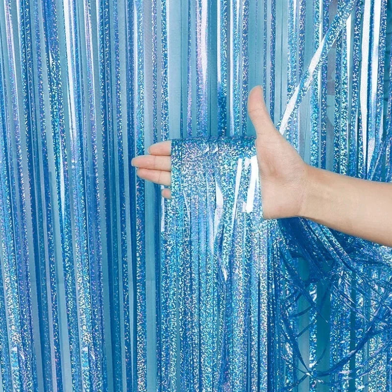 A hand is touching a shimmering blue metallic foil tinsel fringe backdrop curtain.