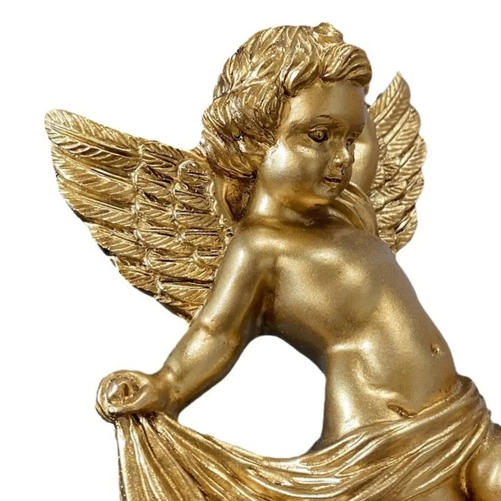 A golden cherub angel sculpture with feathered wings and draped fabric.