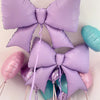 Purple and teal bow-shaped foil balloons tied together for party decorations