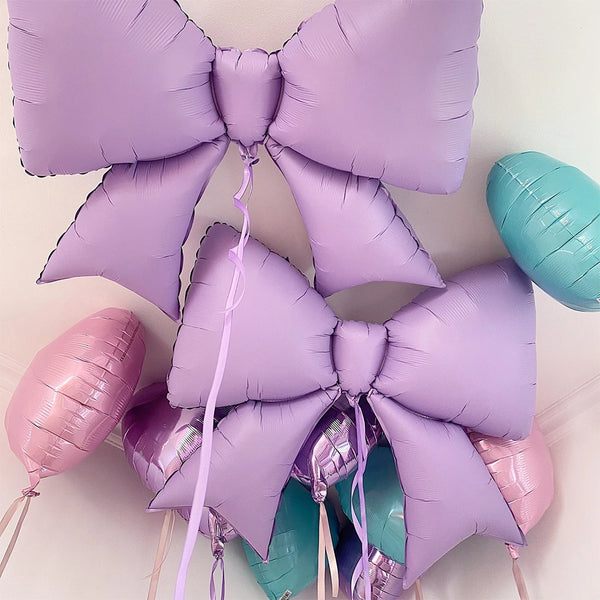 Purple and teal bow-shaped foil balloons tied together for party decorations