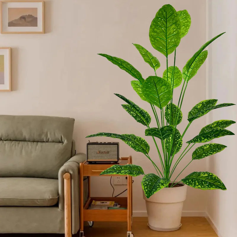A large artificial tree with lush green leaves in a white pot displayed indoors.