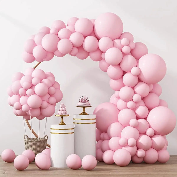A large archway made of pastel pink balloons decorated with white and gold accents.