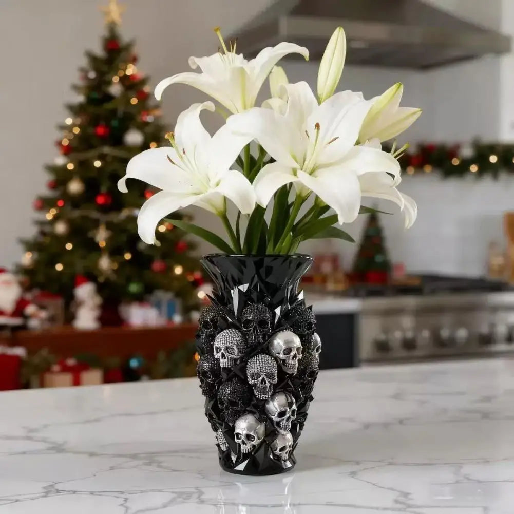 Un vase décoratif noir rempli de lys blancs et de crânes sur une surface de marbre blanc.
