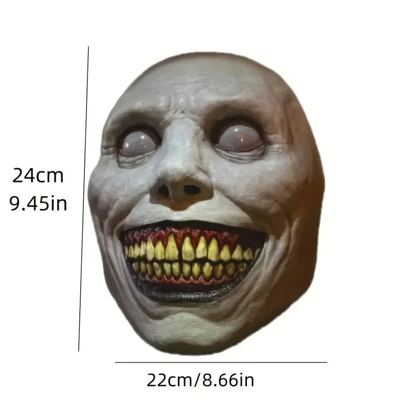 A realistic smiling demon latex mask with a pale face and prominent teeth.