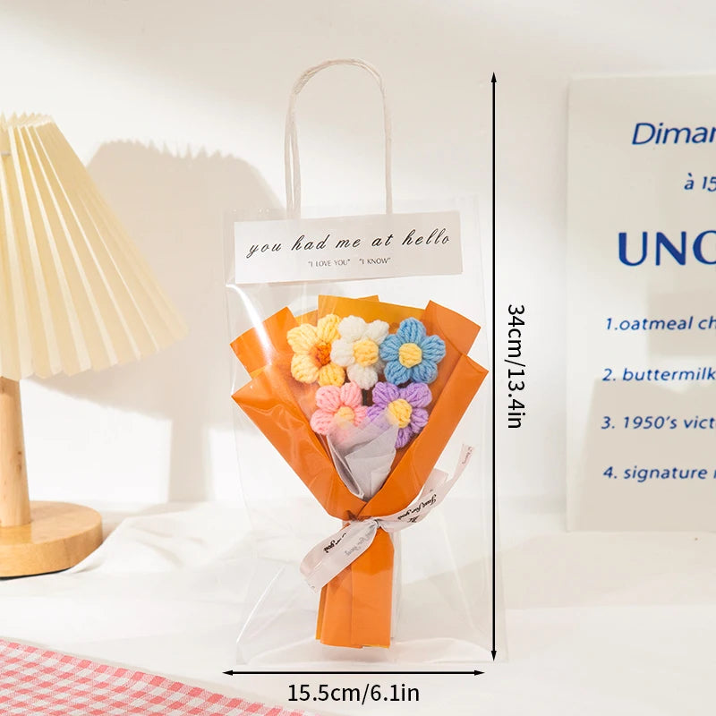 A clear plastic bag containing an orange crochet flower bouquet with a tag and ribbon.