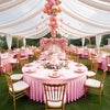 A pink stretch spandex round tablecloth with a skirt set up for an elegant outdoor event.
