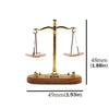A vintage miniature balance scale with a brass frame and wooden base, used for decor.