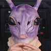 A close-up of a purple alien full-face latex mask being held by hands.