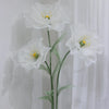 A large artificial silk white poppy flower displayed on a green stand against a white background.