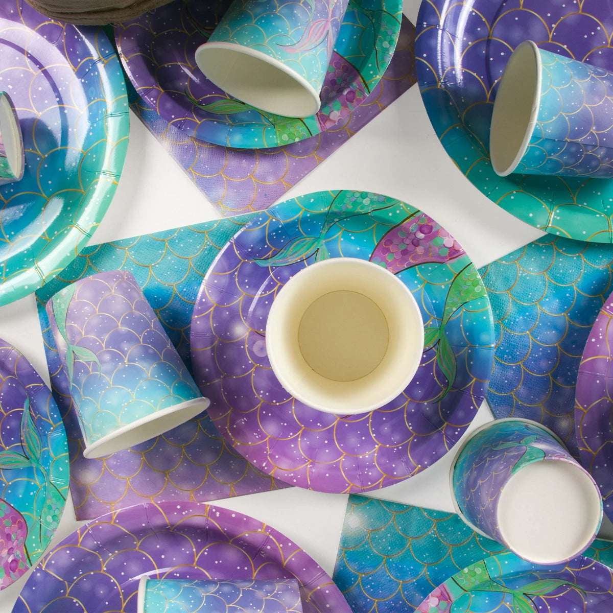A purple and teal Under the Sea Mermaid Party tableware set featuring plates, cups, and napkins.