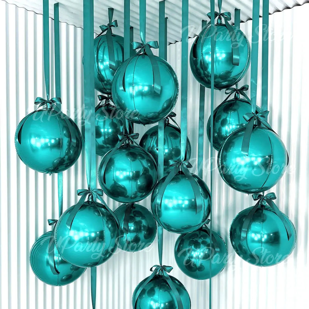 A collection of teal and silver round foil balloons with ribbons hanging vertically.