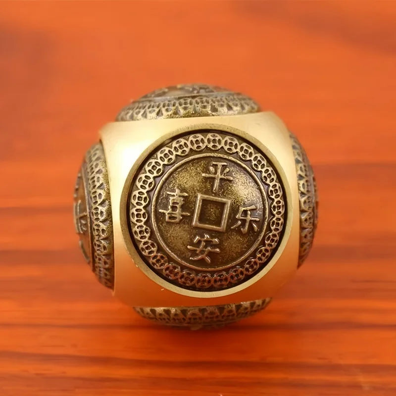 A brass Chinese lucky coin spinner fidget toy with intricate patterns resting on a wooden surface.